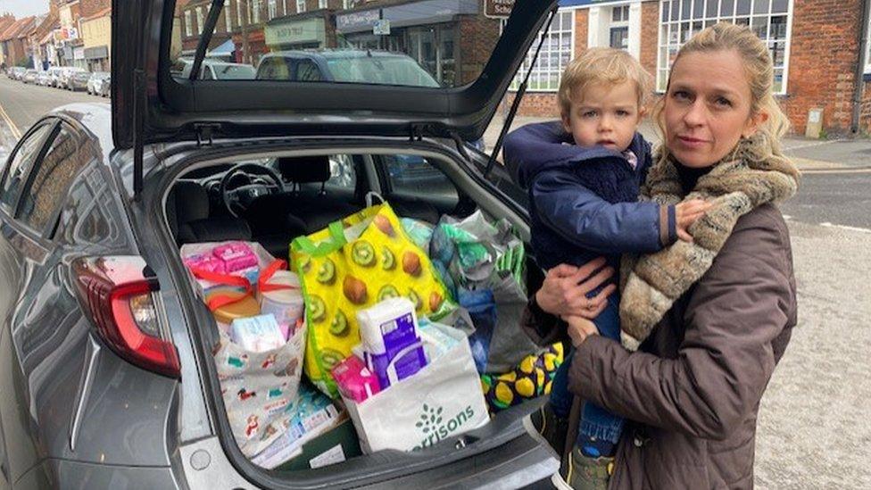 Marta Libera standing by a car boot full of donations