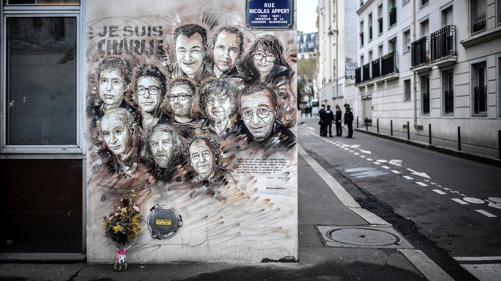 Policemen are seen next to a painting in tribute to members of Charlie Hebdo newspaper