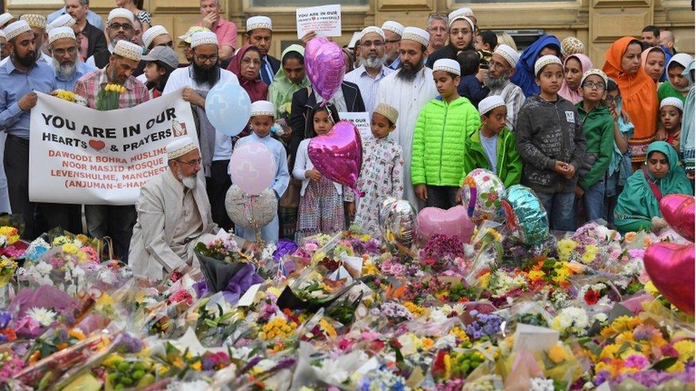 Members of the Muslim community look at floral tributes