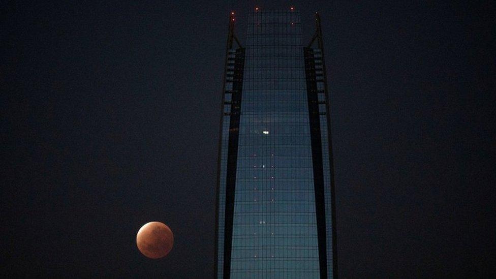 The partial lunar eclipse is seen next to the Gran Torre building in Santiago, Chile