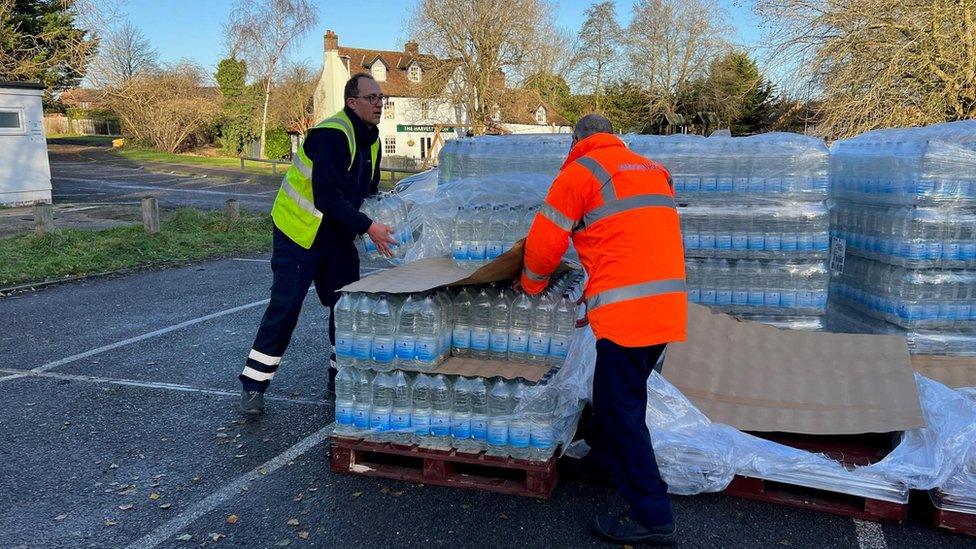 Two men handling bottled water on pallets