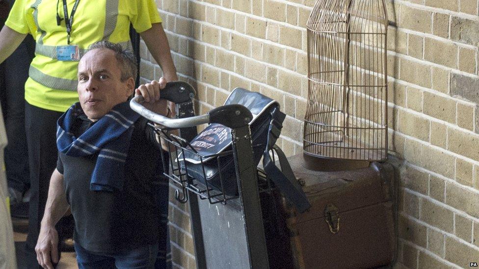 Warwick Davis, who played Professor Flitwick in the Harry Potter films, poses with the Platform 9 and 3/4 trolley