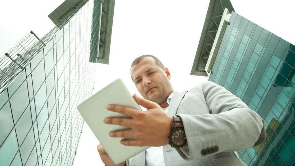 Man with tablet outside buildings