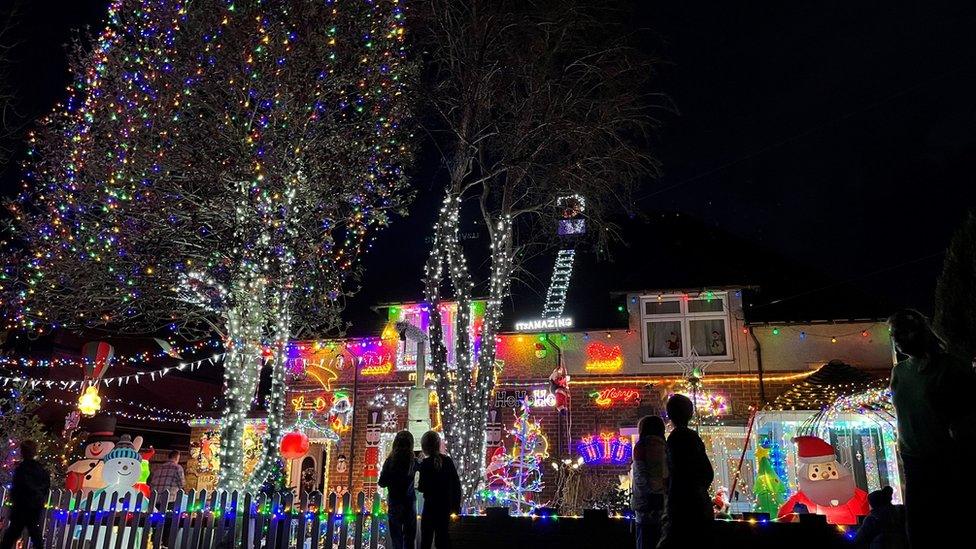 Local residents look at houses illuminated by Christmas lights on Stoneyfield Cottages in Eastergate, West Sussex.