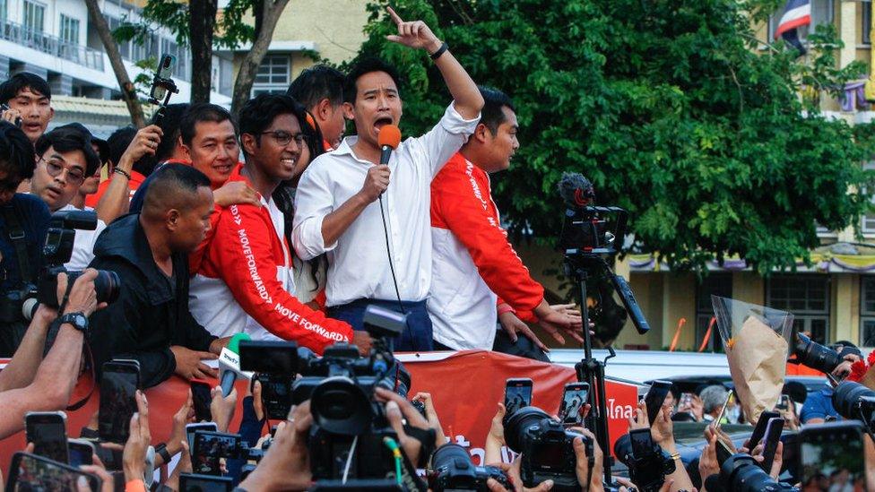 Pita Limjaroenrat speaks surrounded by supporters and the media