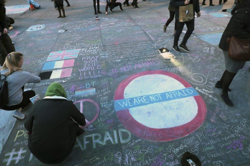 People write messages of support on the ground during a candlelit vigil at Trafalgar Square on 23 March 2017 in London, England