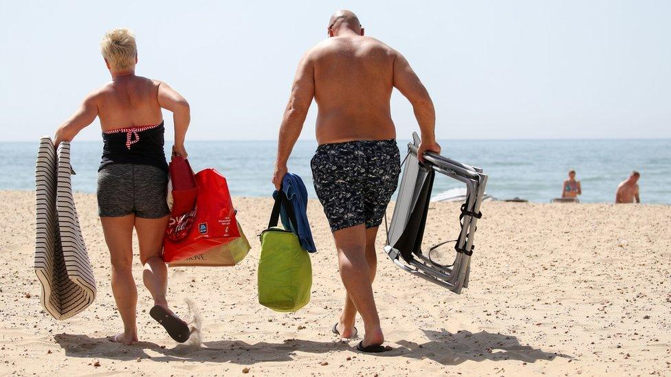 A couple make their way across the sand with their belongings on Bournemouth Beach in Dorset