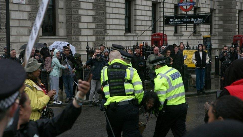 A protester is led away by police officers during an anti-lockdown protest in Westminster