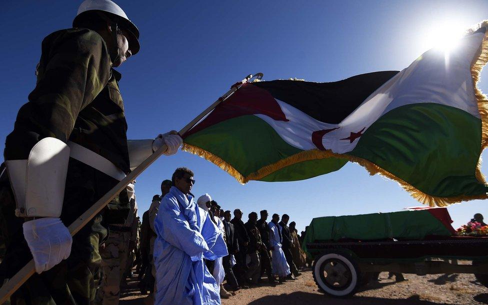 A member of the Sahrawi People"s Liberation Army holds a flag of the disputed territory of Western Sahara during the funeral of Polisario Front"s secretary general, Mohamed Abdelaziz, on June 4, 2016 in Bir Lahlou, some 220 kilometres (137 miles) southwest of the Algerian town of Tindouf. Abdelaziz, who was in his late 60s, had led the Algeria-backed Polisario since 1976, three years after the group was founded to struggle for independence for the territory