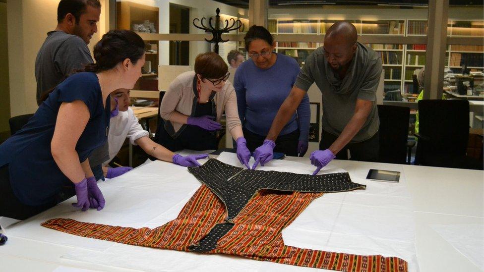 Collections officer Abigael Flack shows volunteers a textile from Syria