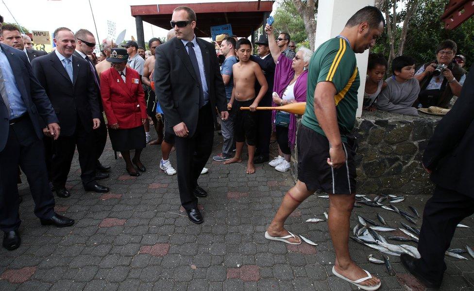 Mr Key (left), along side other people, with fish on the path in front of him