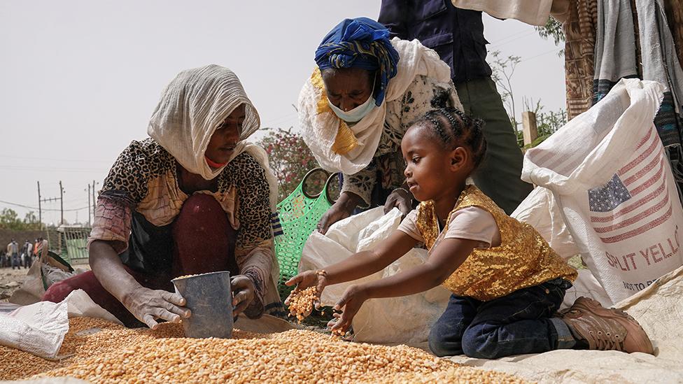 A girl in Mekele, Ethiopia helps divide a bag of lentils into portions. The food aid has been sent to help people at risk of famine.