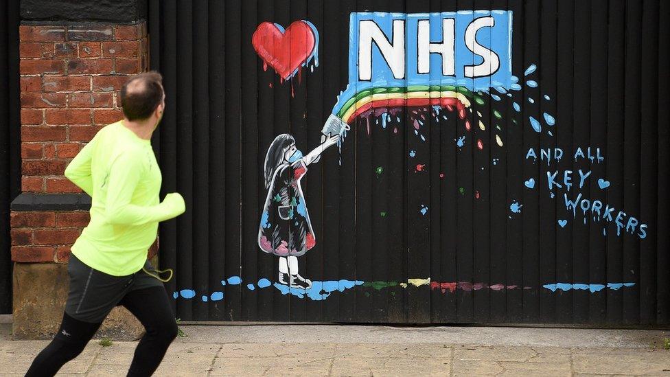 man-runs-by-painting-for-nhs-on-wooden-doors