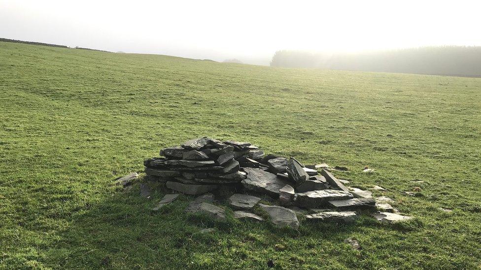 The wind and the elements have knocked down some of the stone cairn