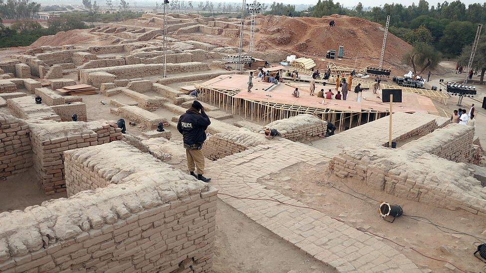 A policeman watches as Pakistani workers prepare a stage around the ancient ruins ahead of the cultural heritage festival in Mohenjo Daro, the UNESCO World Heritage site around 425 kilometres north of the port city of Karachi, on January 30, 2014