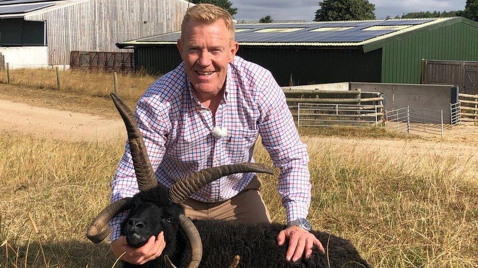 Adam Henson on the Cotswold Farm Park in front of a barn with solar panels