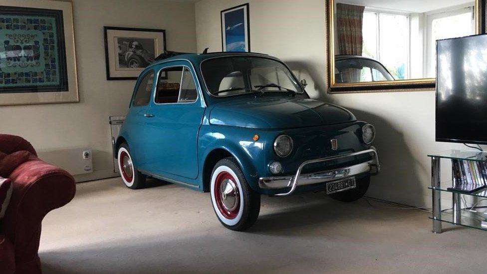 A teal green Fiat 500 in a living room