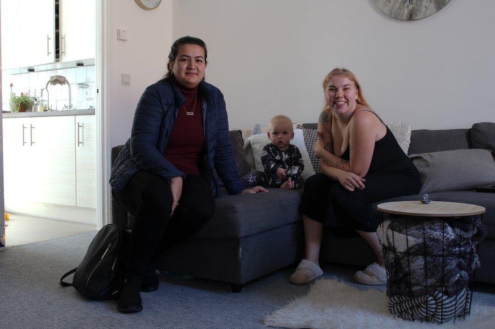 Aziza and Alex sit on the sofa with baby Benjy