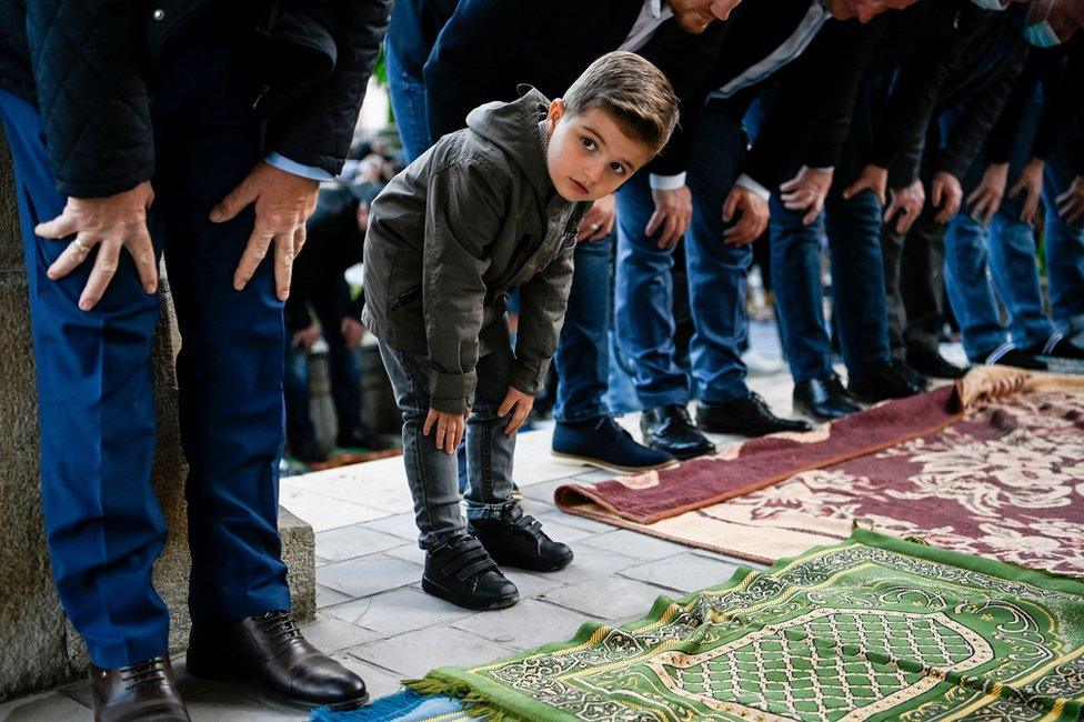 A young boy looks on as he takes part in Eid prayers in Pristina, Kosovo