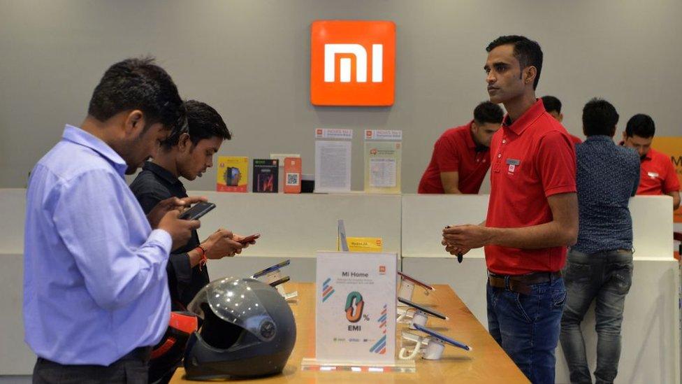 In this photograph taken on August 20, 2019, customers inspect smartphones made by Xiaomi at a Mi store in Gurgaon.