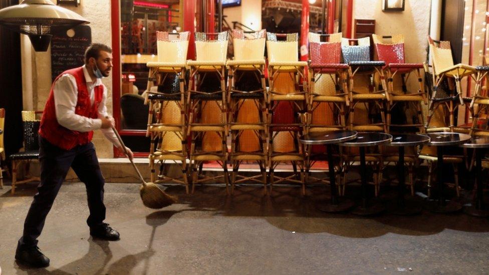 A staff member prepares to close a restaurant minutes before the late-night curfew in Paris