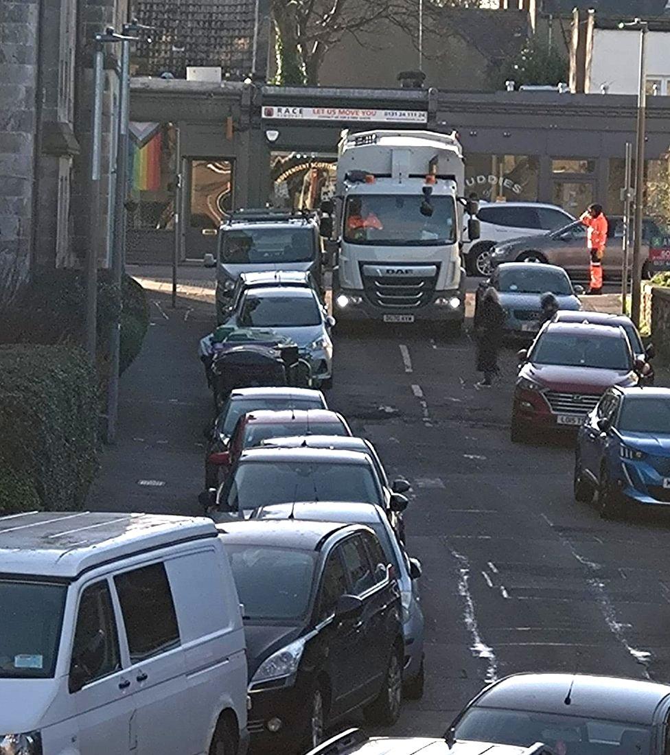 Bin lorry reversing down street in Edinburgh, blocked by drivers parking on pavements