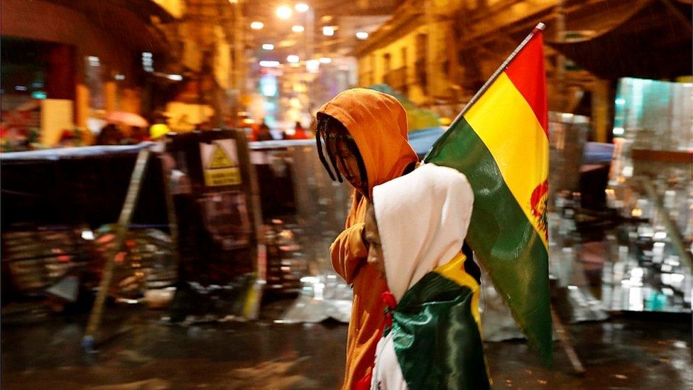 People walk past a barricade during a protest against Bolivia's President Evo Morales in La Paz, November 10, 2019