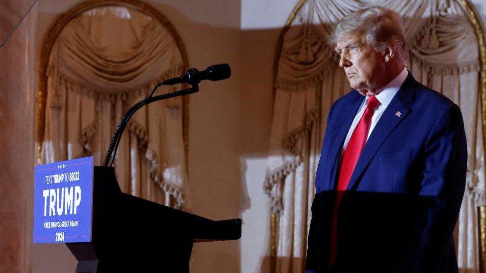 Donald Trump stands behind a podium at a campaign event