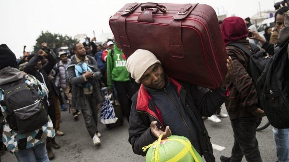 Migrants carry their luggage as they prepare to leave the Jungle camp. Photo: 24 October 2016