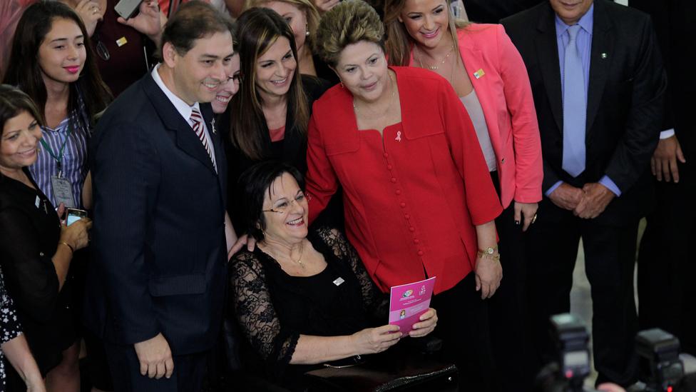 Brazil's President Dilma Rousseff (in red) poses with women's rights activist Maria da Penha during the launch of the "Woman: Living without Violence" program at the Planalto Palace in Brasilia March 13, 2013. The program seeks to prevent violence against women through educational campaigns. Maria da Penha, who fought for 20 years to see her assailant arrested, has a law named in her honor for victims of domestic violence against women.