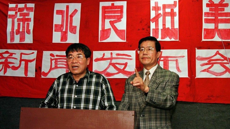 Xu Shuiliang (L) answers questions from reporters 01 April at a news conference in Queens, NY. The sign in the back announces that the exiled Xu has arrived in the US. At right is a spokesman for the Chinese Democracy and Justice Party Wang Bingzhang.