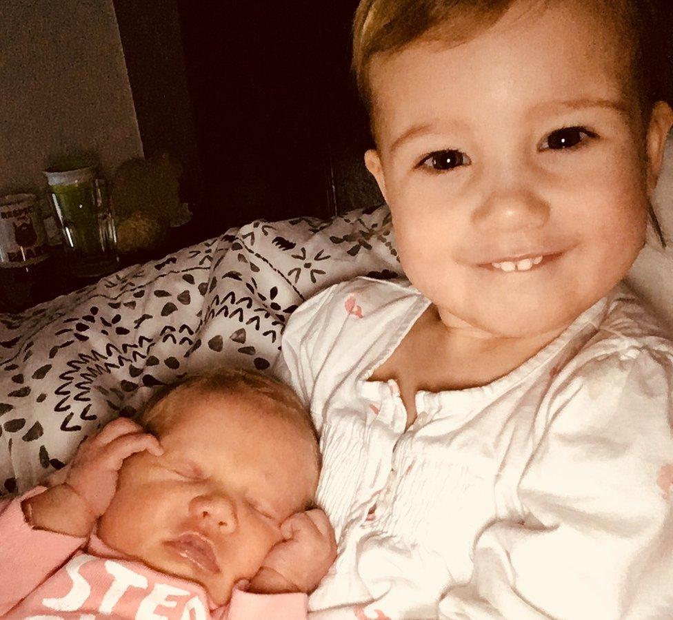 Amelia cuddling her sister Eliza on the baby's first morning at home