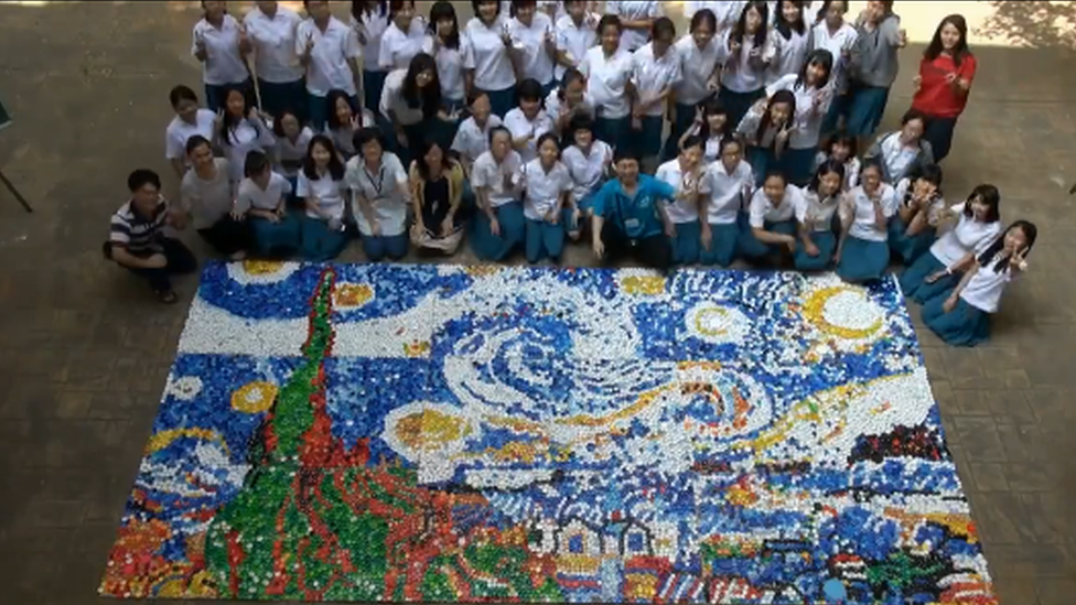 The students standing in a group behind the completed artwork