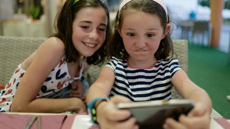 Stock image of two girls using a phone