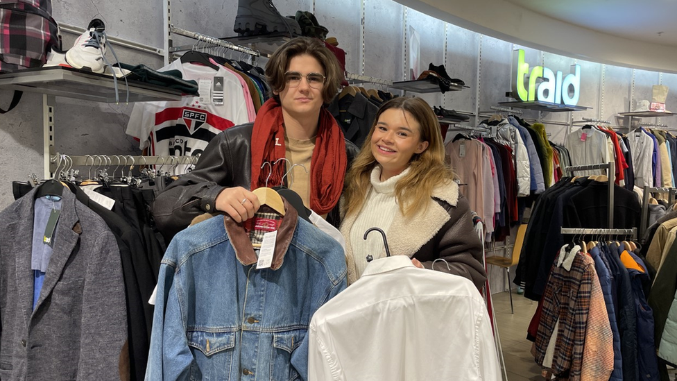 Isaac and Lauren with garments from the Charity Super.Mkt