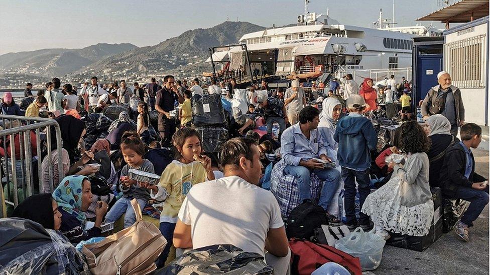 Refugees and migrants wait to board a ship at the port of Mytilene, in the island of Lesbos on September 2, 2019.