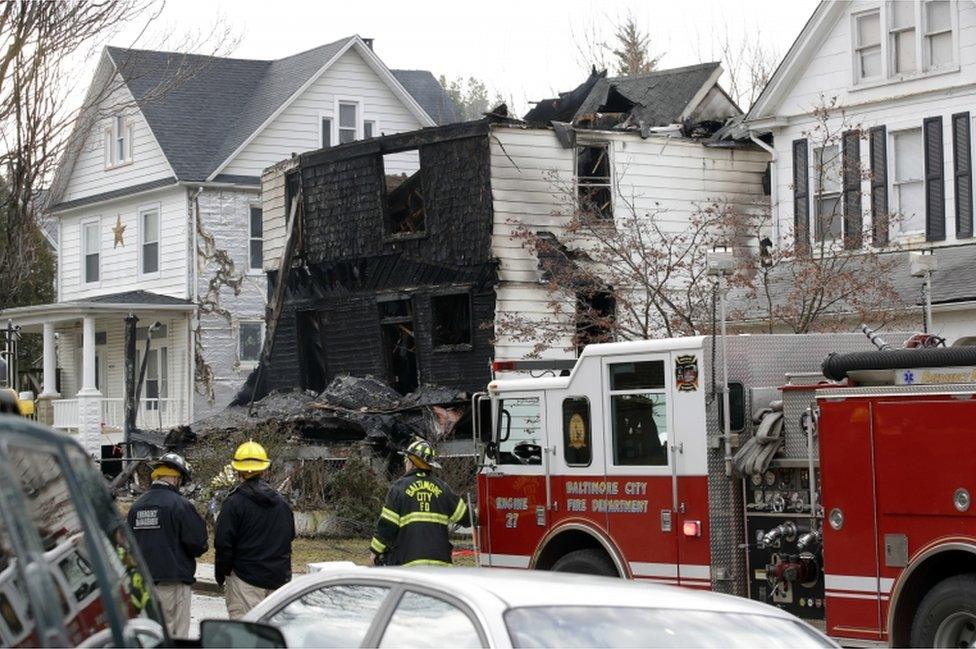 Fire officials stand at the scene of an early morning house fire in Baltimore on January 12, 2017.