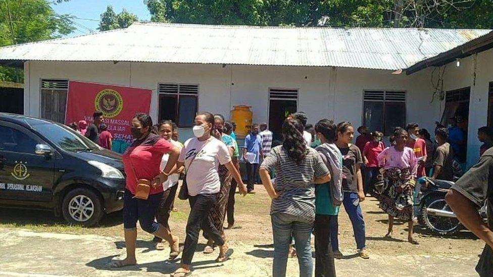 Villagers stand outside a building in Maumere in East Nusa Tenggara on Flores island on December 14, 2021, after a 7.3-magnitude earthquake struck off the coast in eastern Indonesia.