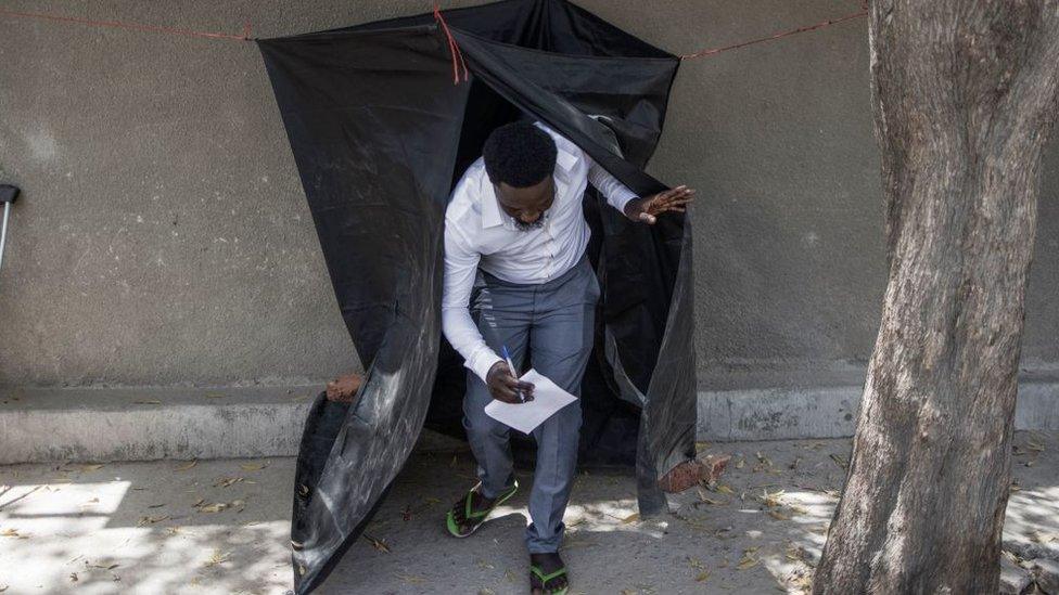 A man carries a marked ballot as he leaves a voting booth hanged on the side of the road at a polling station in N'djamena on April 11, 2021.