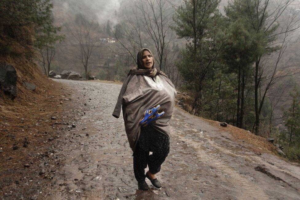 A Kashmiri woman carries a newborn baby inside her ‘phiran', a traditional Kashmiri dress, as she escapes artillery fire.