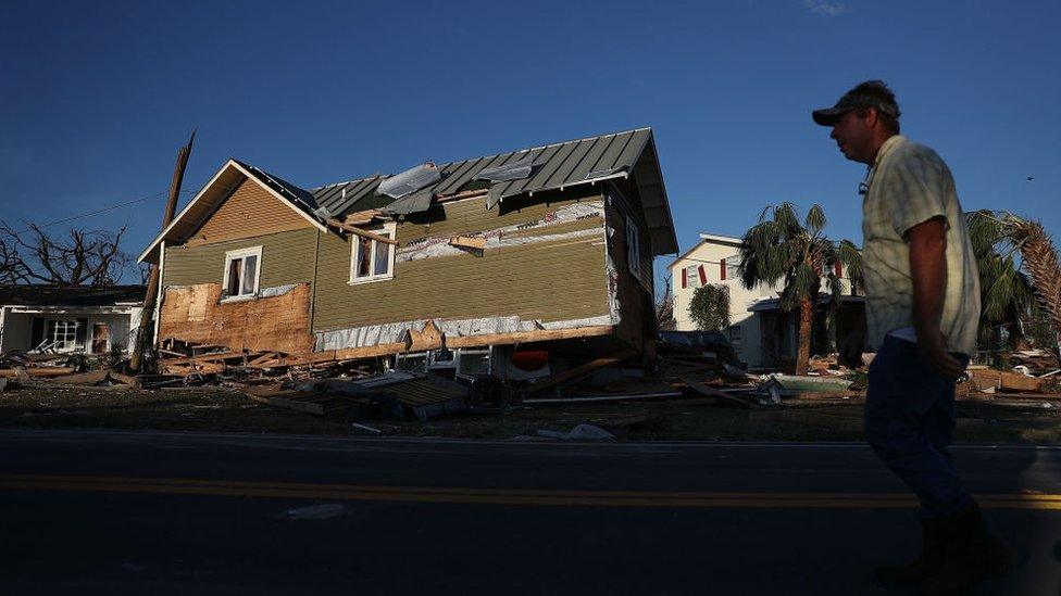 A man in Mexico Beach, Florida walks past a home that was knocked from its foundation