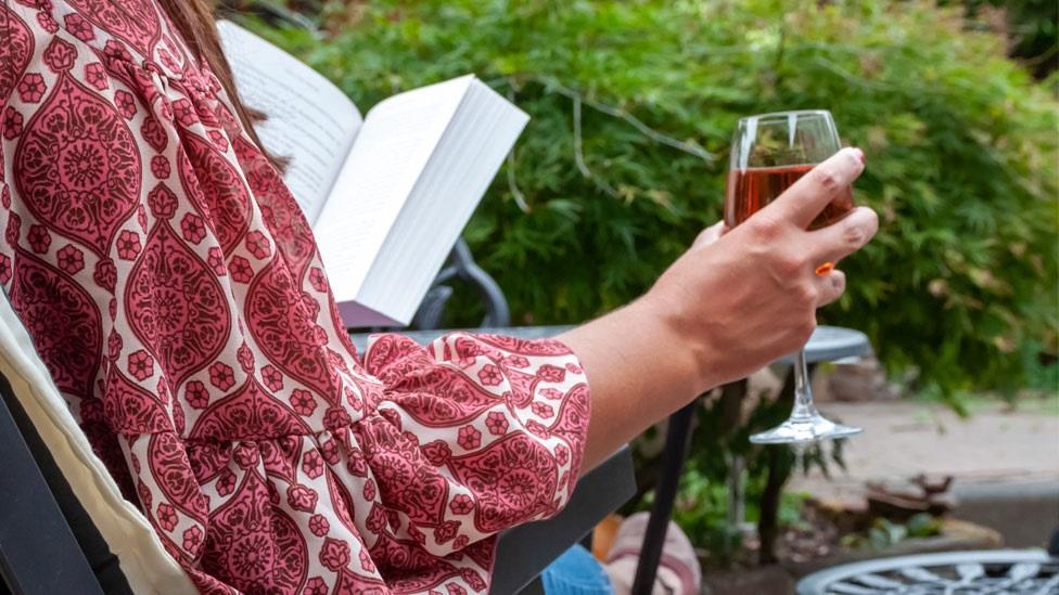 A woman drinking in a garden