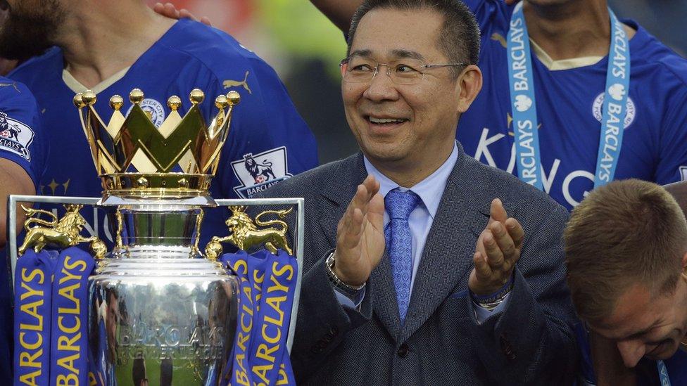 Vichai Srivaddhanaprabha applauds beside the trophy as Leicester City celebrate becoming the English Premier League soccer champions at King Power stadium