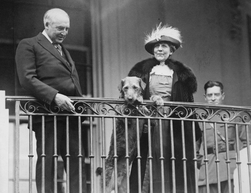 President Warren G Harding and First Lady Florence Harding stand on a balcony with their dog