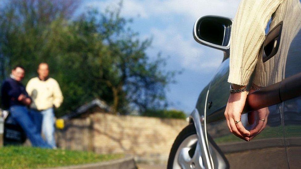 Person with hand hanging out of a car window