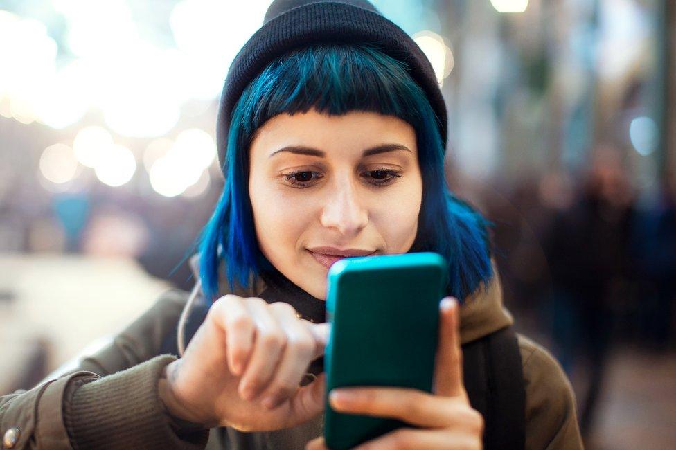 Girl with dyed blue hair looking at her phone