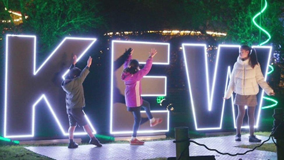 Children dance in front of a Kew Gardens signs