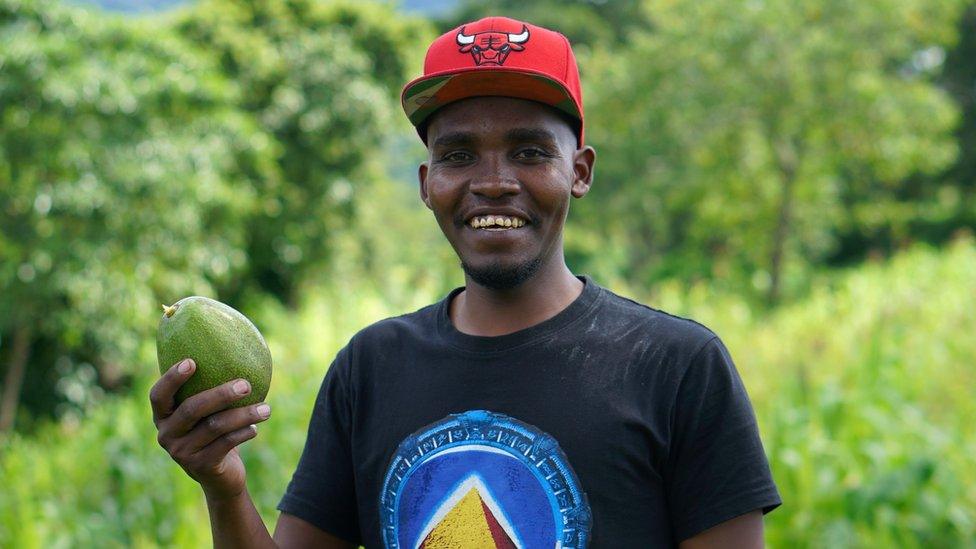 Avocado oil press inventor Jesse Oljange in a field with an avocado