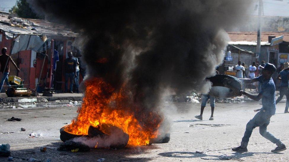 A supporter of presidential candidate Maryse Narcisse burns tires to protest the final election results in Port-au-Prince, Haiti