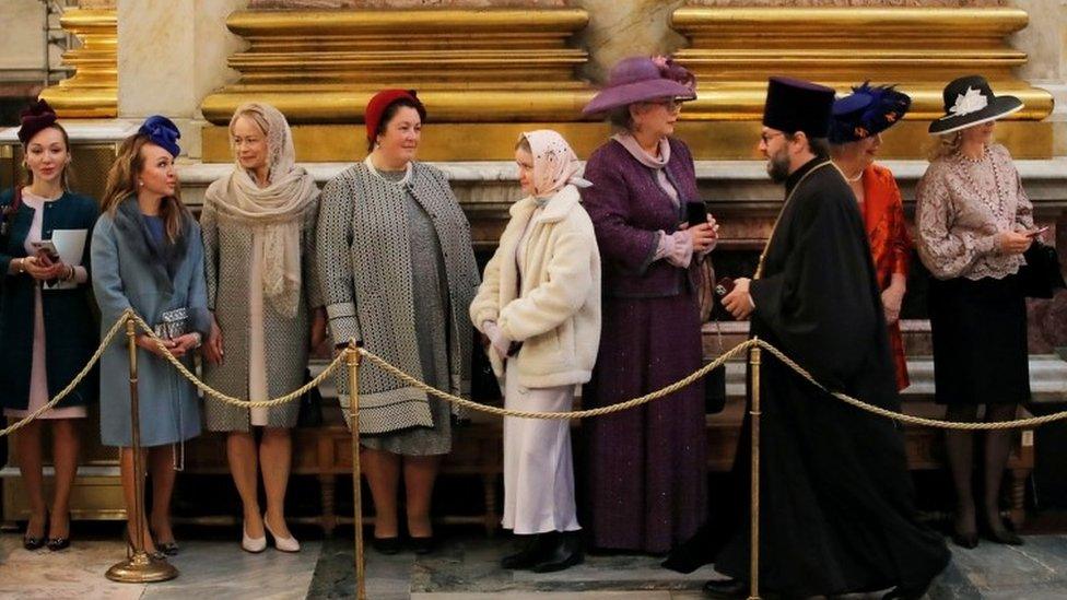 A priest walks past guests during the wedding ceremony